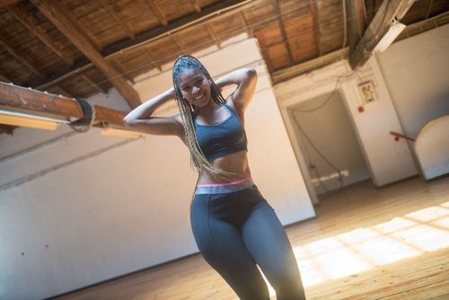 Free Athletic woman with braids in a gym, smiling confidently wearing active wear. Stock Photo