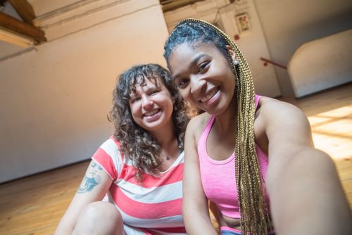 Free Two women, one with braided hair, smile as they take a selfie indoors. Stock Photo