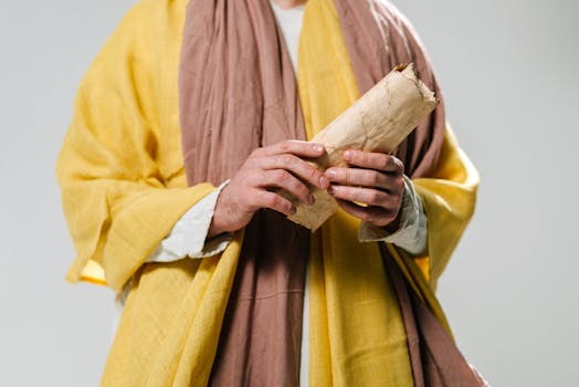 Close-up of hands holding an ancient scroll wearing traditional robes.
