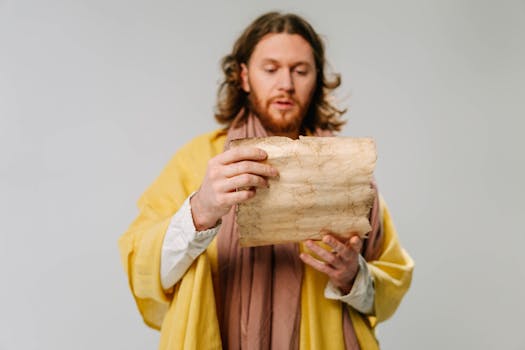 Man with long hair reads an ancient scroll. Historical attire suggests a religious or scholarly theme.