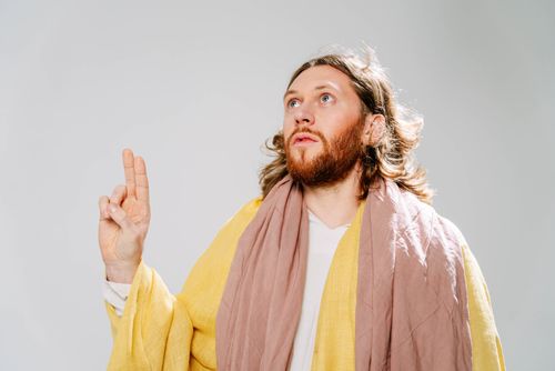 Free Portrait of a man with a beard, wearing a robe, making a hand sign. Neutral background. Stock Photo