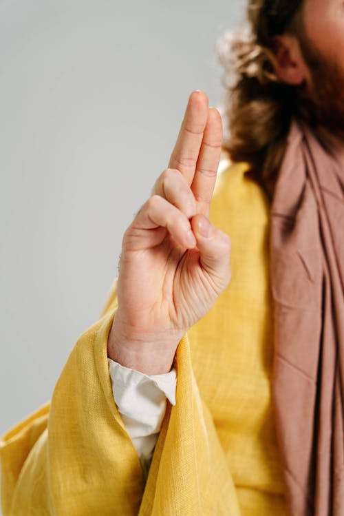 Man in Yellow Robe and Brown Scarf Representing Jesus Christ Doing Peace Sign