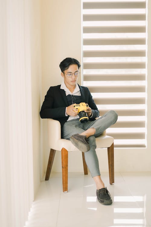 Gratis arkivbilde med asiatisk mann, digitalt speilreflekskamera, lenestol