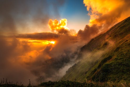 Orange Clouds on a Sunset Sky Over Green Hills