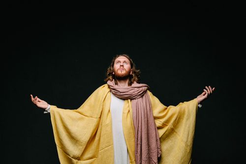 Free Portrait of a man in robes with arms outstretched against a dark background, evoking a spiritual theme. Stock Photo