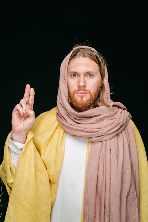 Man in Yellow Robe and Brown Scarf Representing Jesus Doing a Peace Sign