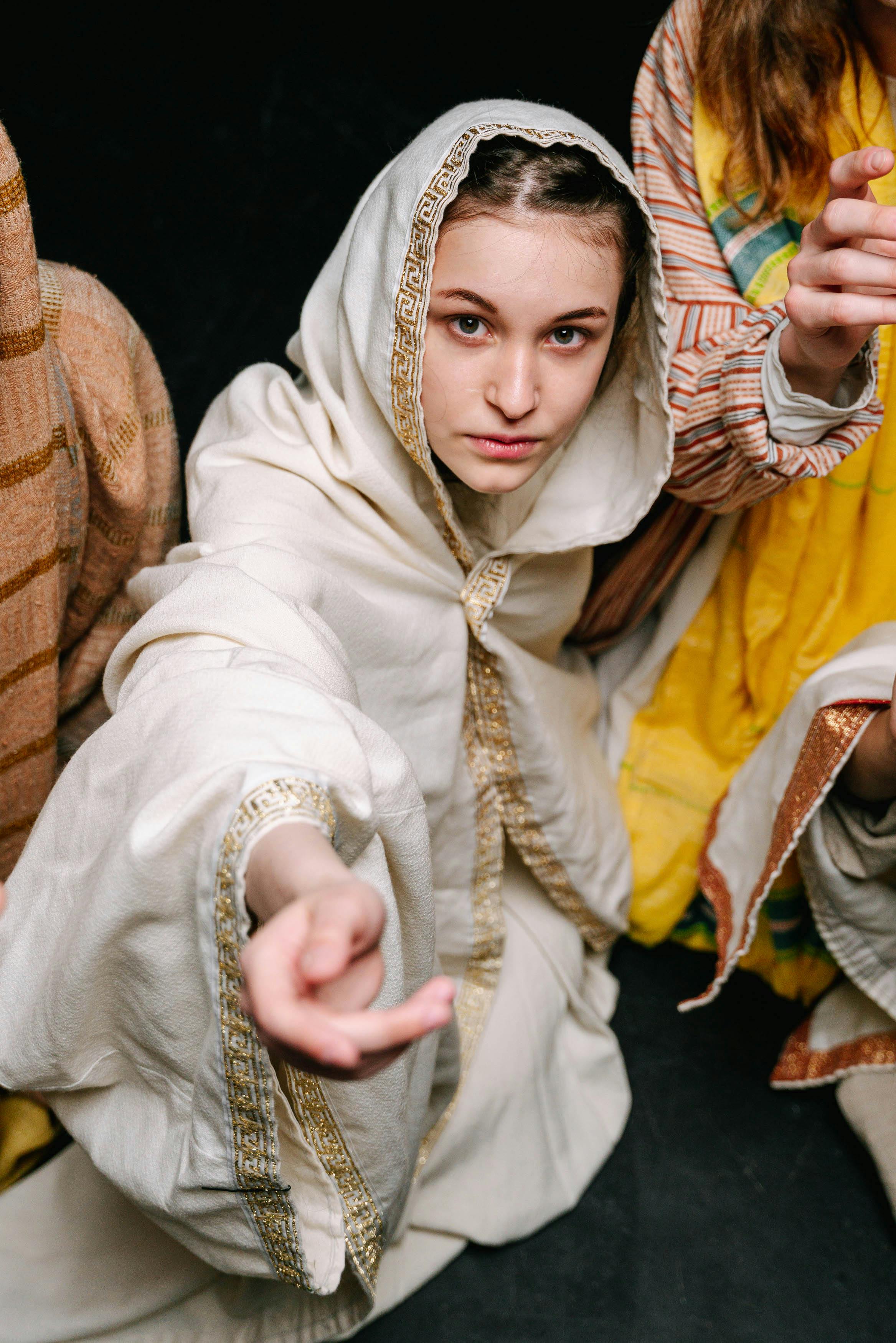 Free Woman in traditional attire kneeling in a dramatic theatre setting. Stock Photo