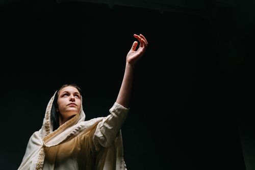 Free A woman wearing a shawl gracefully raises her arm, set against a black background. Stock Photo