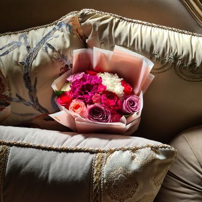 Wrapped bouquet of roses resting on a sofa — photo by خلود محمد on Pexels