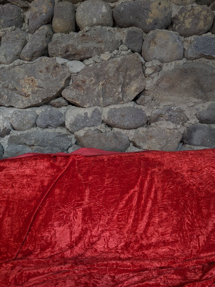 Red Velvet Fabric Against A Rocky Wall 