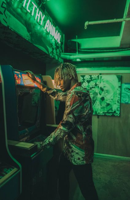 Man enjoying arcade game under vibrant neon lights inside a retro gaming space.