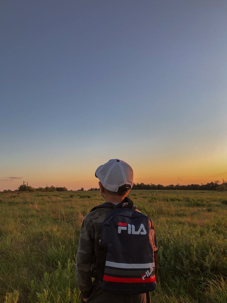 A Boy Wearing A White Cap Carrying A Backpack