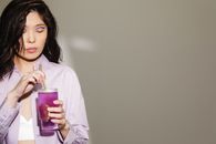 Woman in White Long Sleeve Shirt Holding Purple Glass Mug