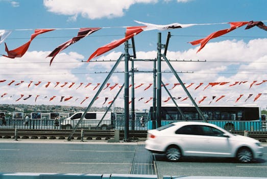 A vibrant urban scene with motion blur cars and red flags on a bridge in Istanbul.