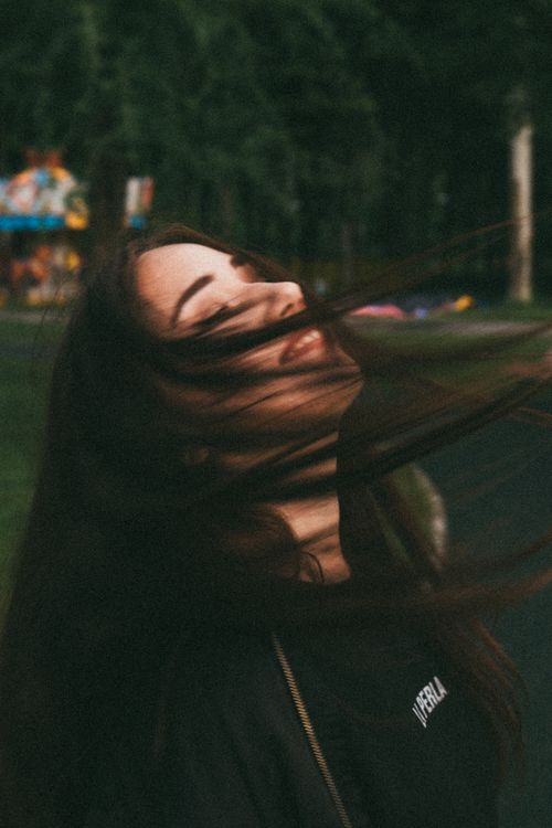 Free Young woman enjoying a moment with hair in motion, embracing the breeze in a natural setting. Stock Photo