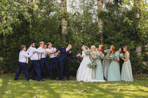 A Bride and Groom Pulling Them by Their Bridesmaids and Groomsmen
