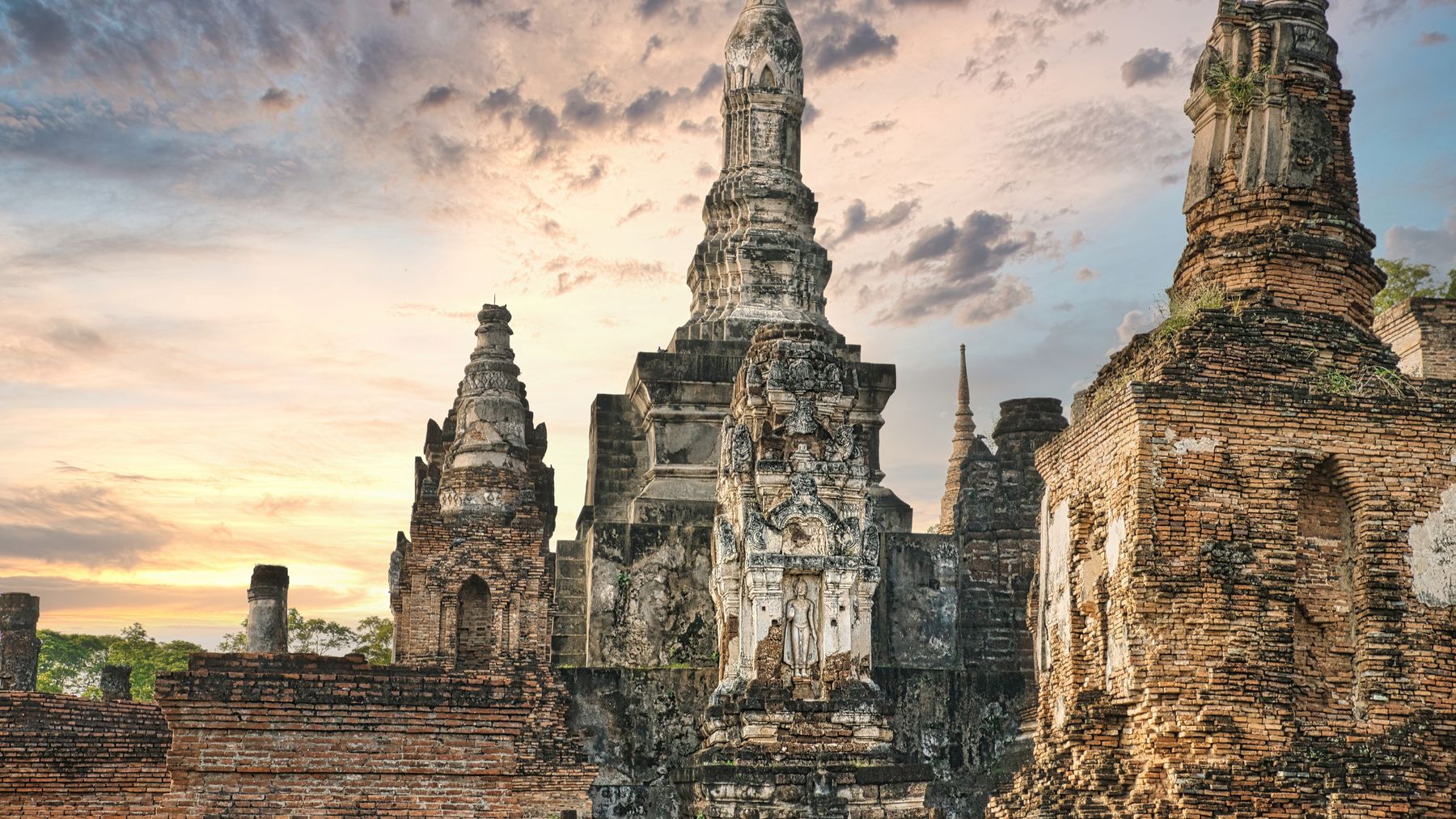 Ancient temple ruins of Wat Mahathat with a stunning sunset sky in Sukhothai, Thailand.