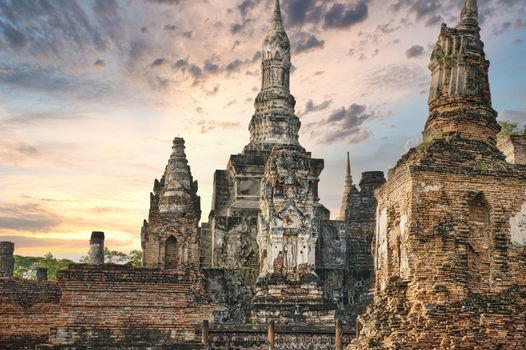 Ancient temple ruins of Wat Mahathat with a stunning sunset sky in Sukhothai, Thailand.