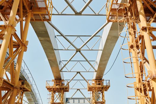 A striking low-angle view of a modern bridge under construction, highlighting beams and steel structures against a clear sky.