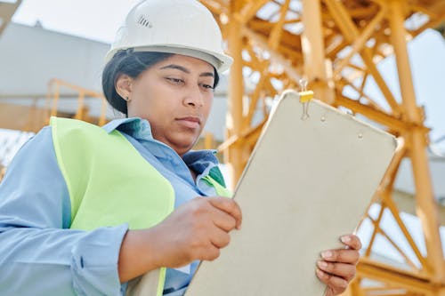 Woman Wearing Safety Helmet Holding a Whiteboard