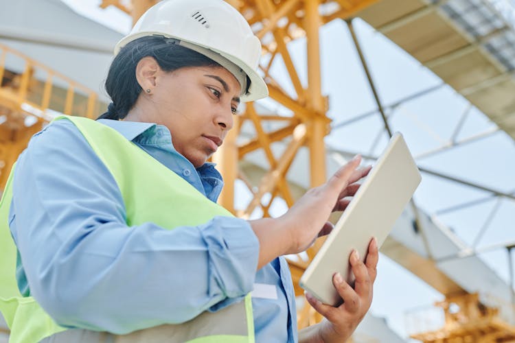 Woman In White Hardhat Holding Silver Touchscreen Device