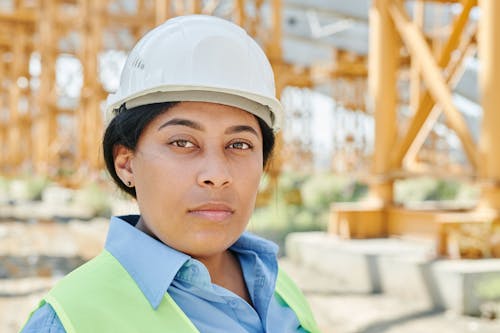Woman in Blue and Yellow Button Up Shirt Wearing White Hard Hat