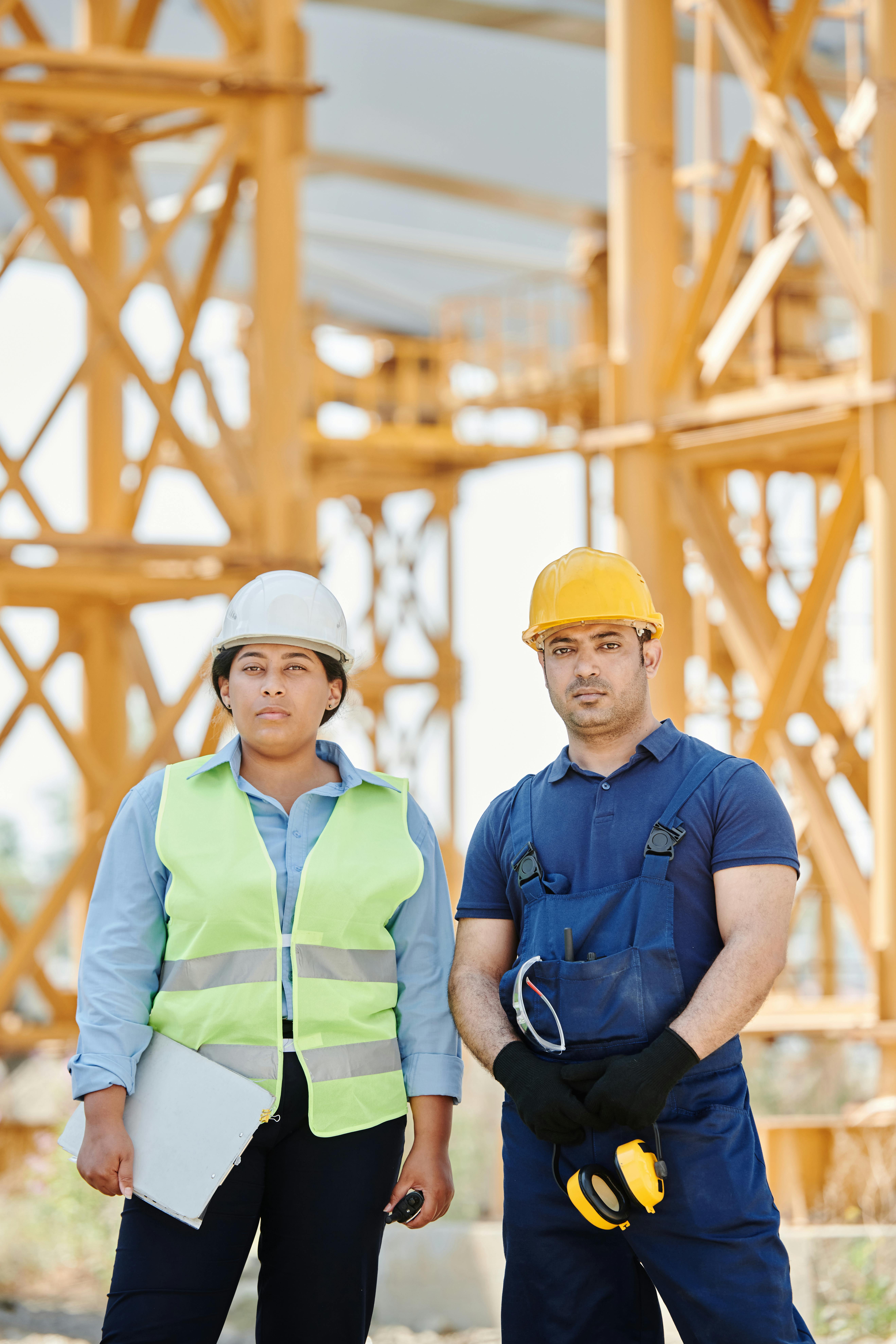 a man and a woman wearing hardhats standing near a metal structure