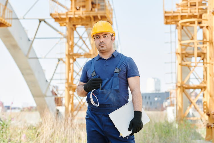 Man In Blue Polo Shirt And Blue Jumper Wearing A Yellow Hardhat