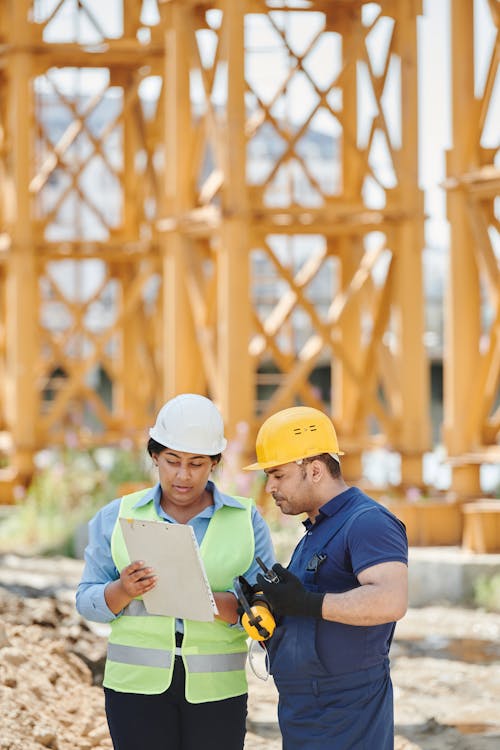 Free A Man and Woman Having Conversation at the Construction Site Stock Photo