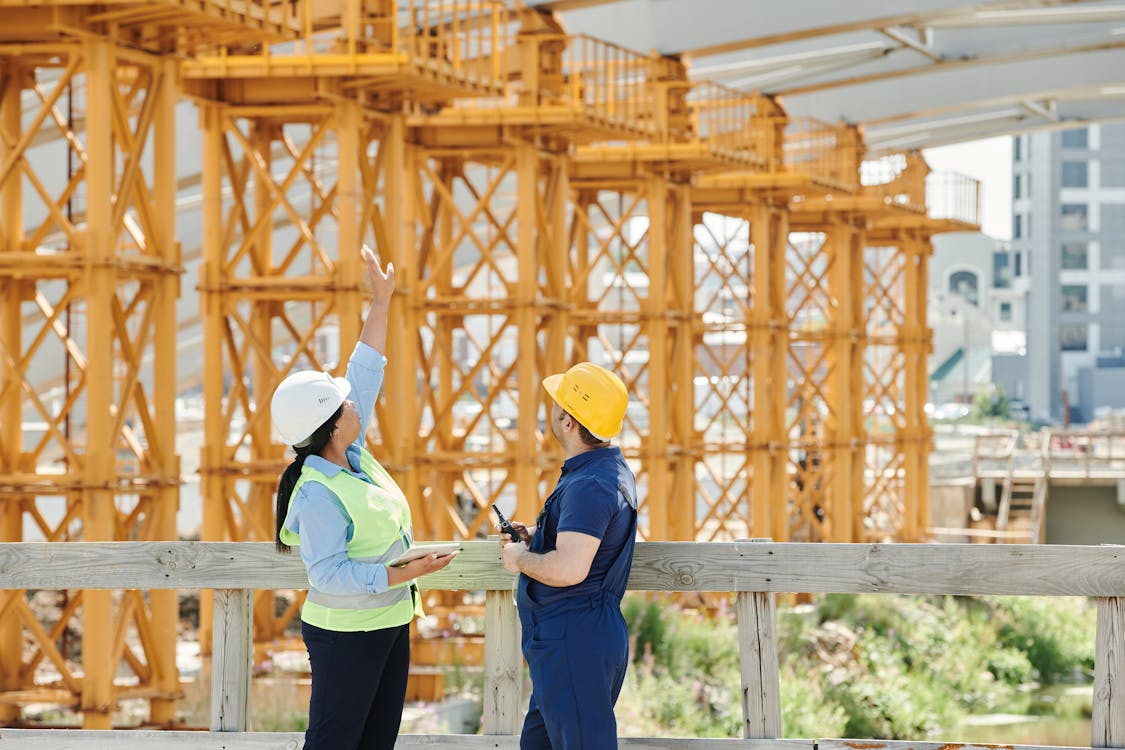 Free A Man and a Woman with Ppe's Talking at a Construction Site Stock Photo
