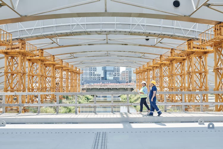 Construction Workers Walking Near Metal Railings