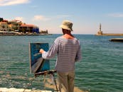 一位画家在希腊海边描绘哈尼亚灯塔的风景