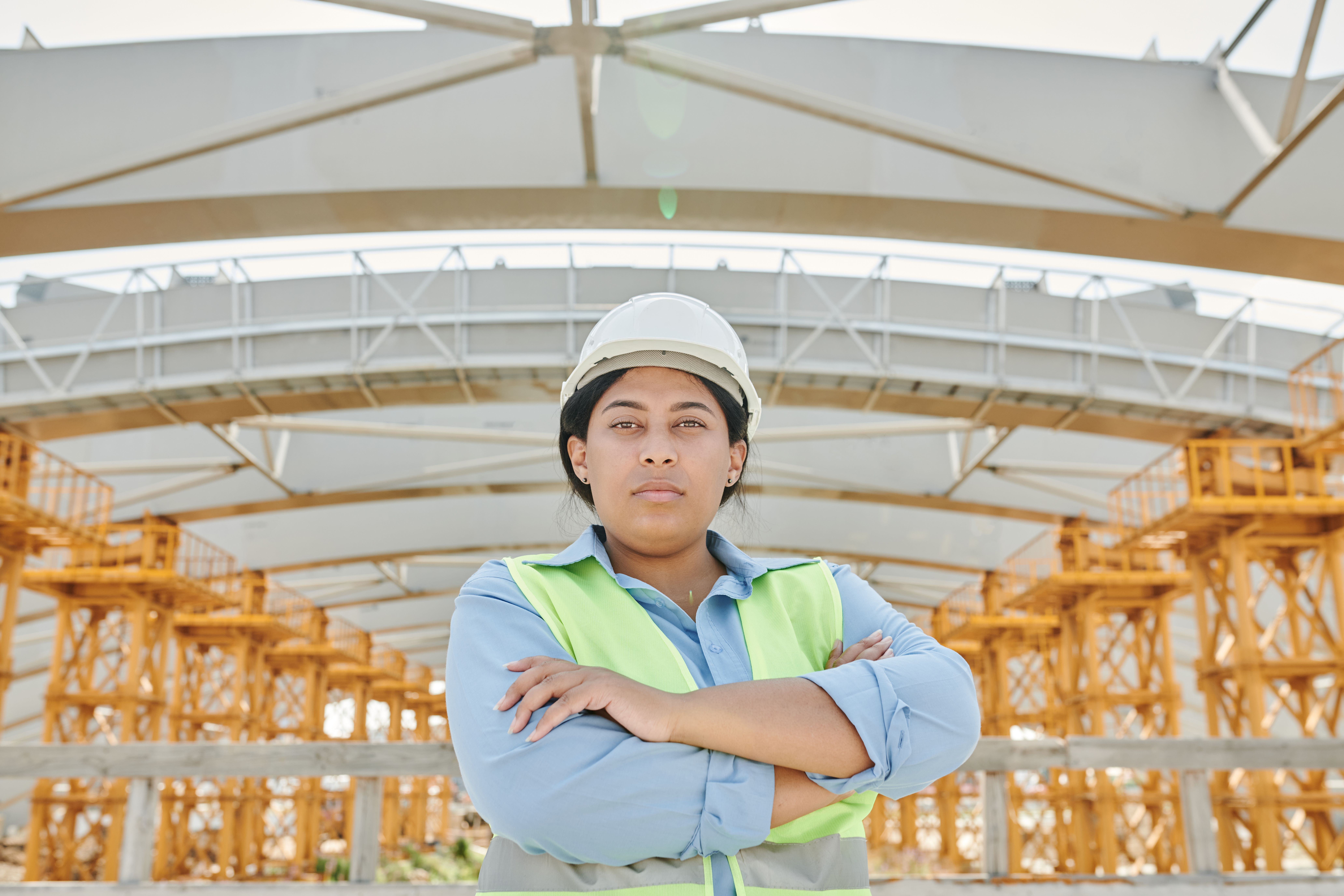 Female engineer in safety gear a t a construction site with steel structure background