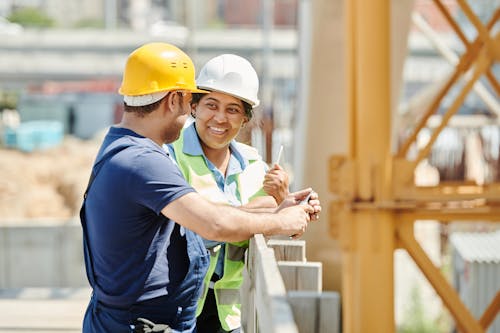 Free A Man and Woman Wearing Hard Hat While Talking Stock Photo