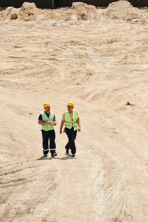 Free Workers Wearing Safety Vest and Hard Hat Walking on the Dry Ground Stock Photo