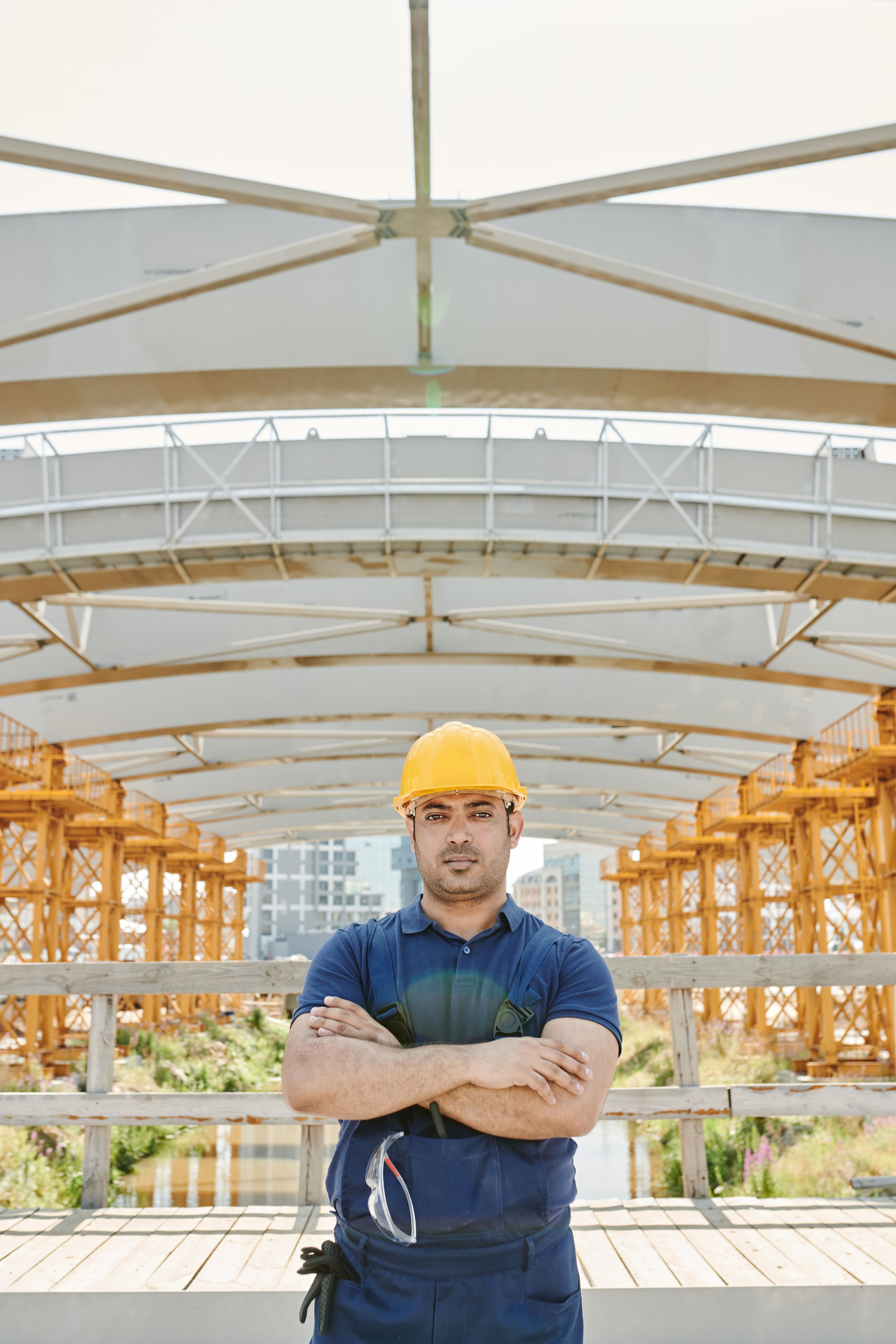 QBCC Mutual Recognition: How to Bring Your Interstate Licence to Queensland 2 Male construction worker with crossed arms at a bridge site with orange scaffolding