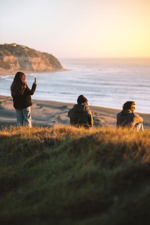 Free Three people enjoy a golden sunset overlooking Matanzas Beach in Chile. Stock Photo