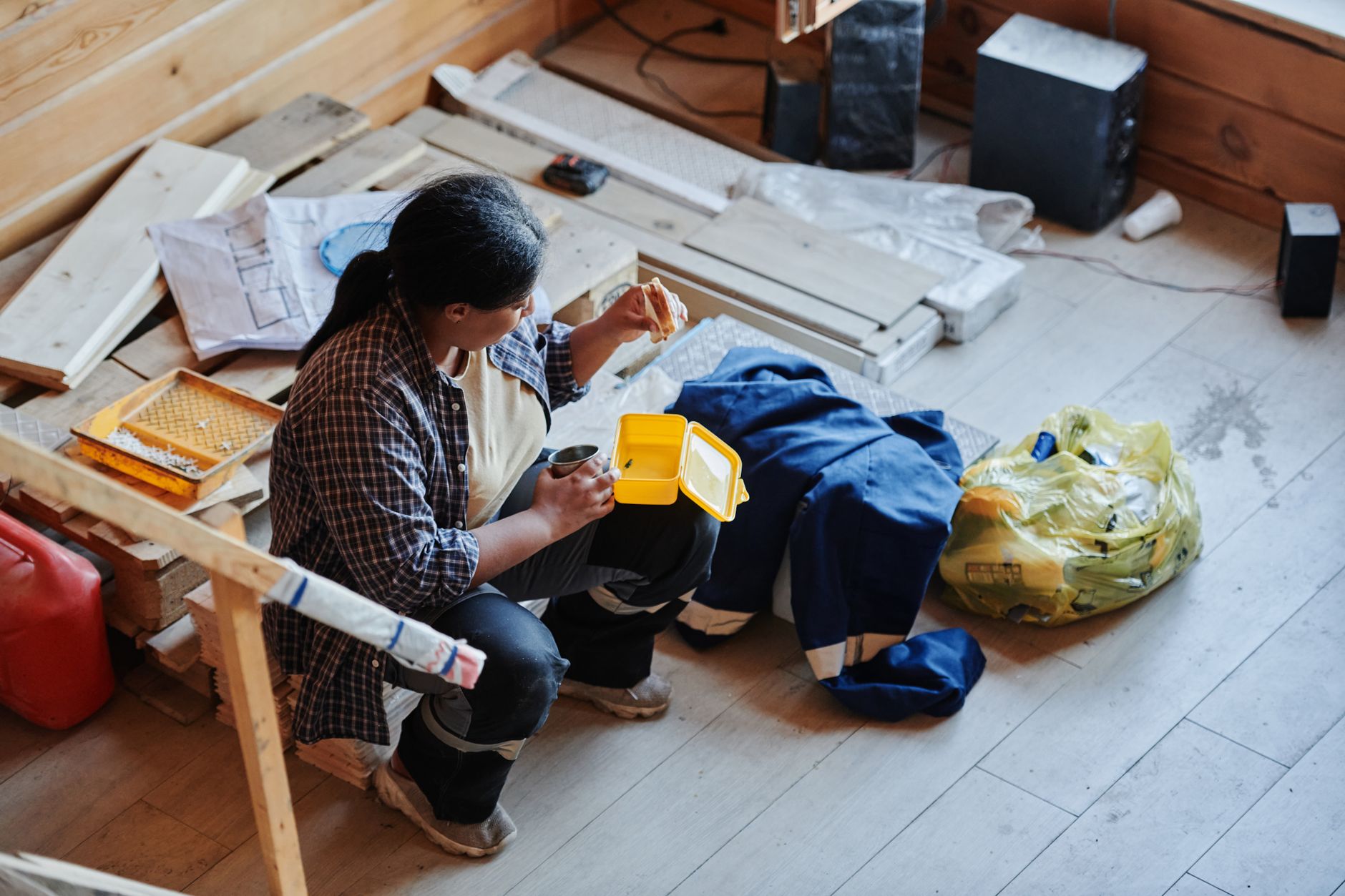 A female construction worker taking a lunch break in a house under renovation, viewed from above