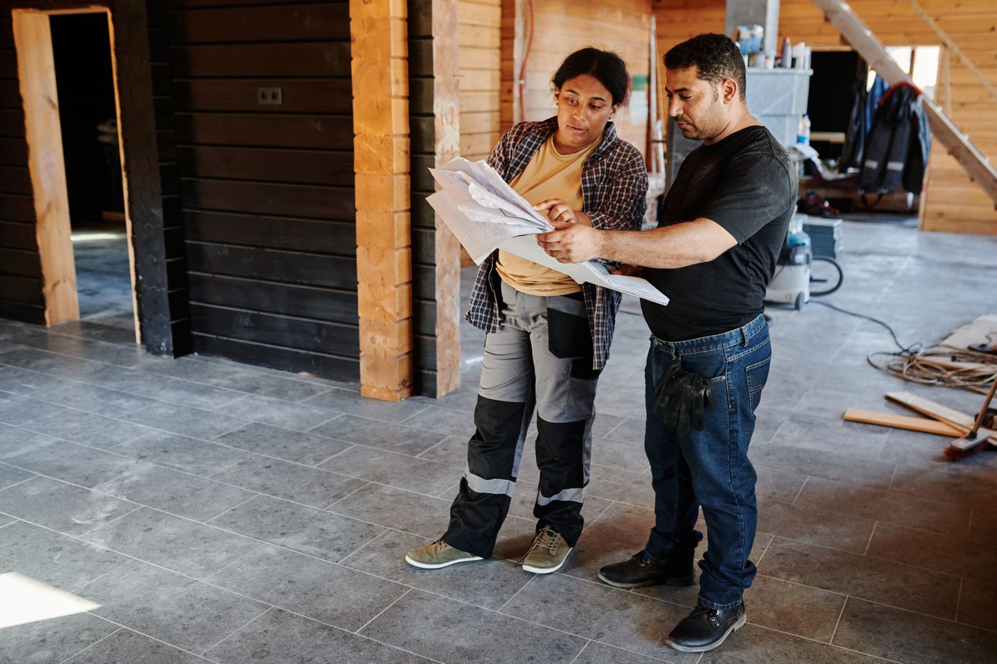Dos técnicos de Castellana Reformas revisando los planos de una vivienda en obra