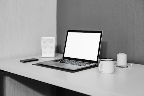 Silver and Black Laptop Beside White Cup on White Table