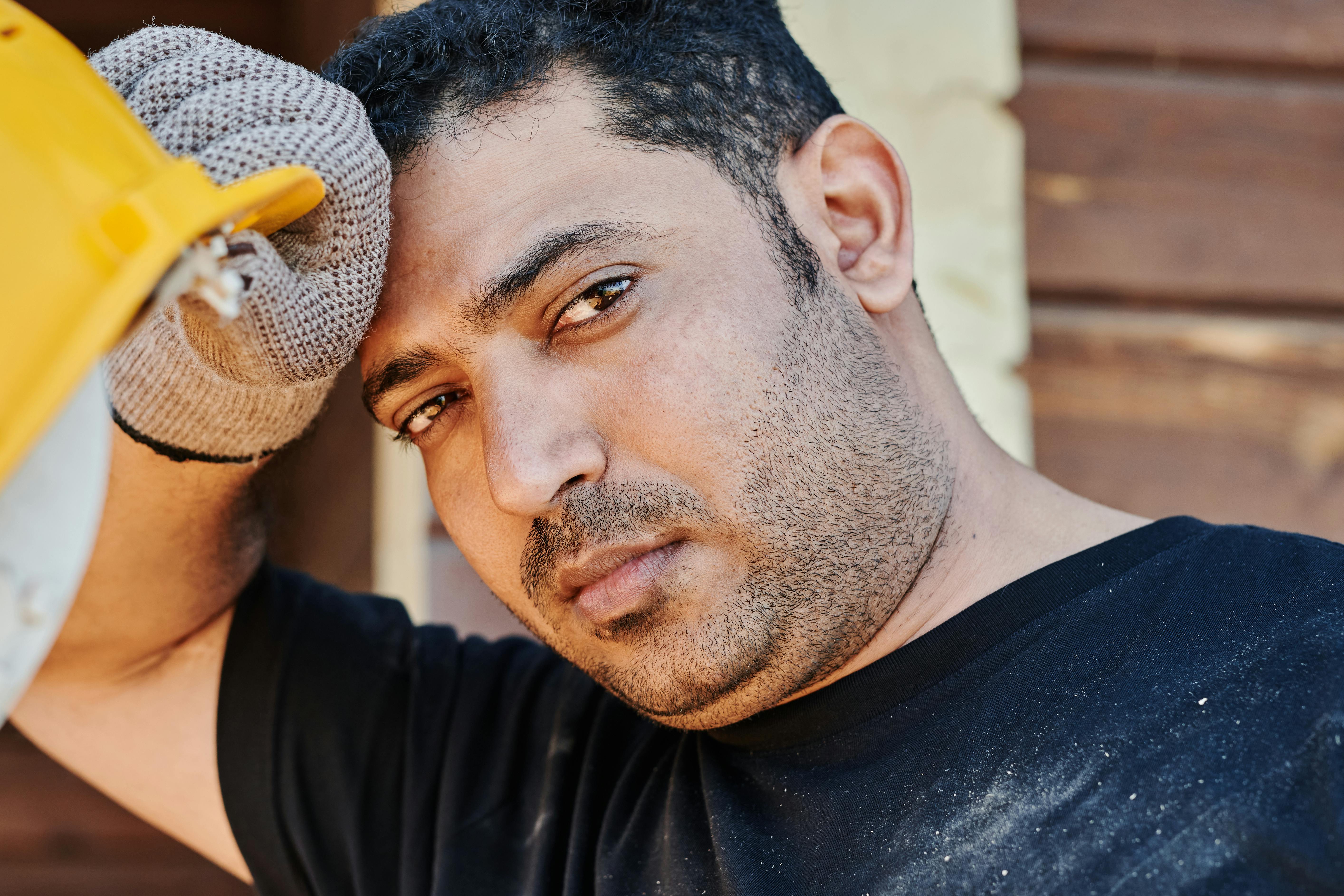 Close-up portrait of a construction worker resting with a helmet in hand.