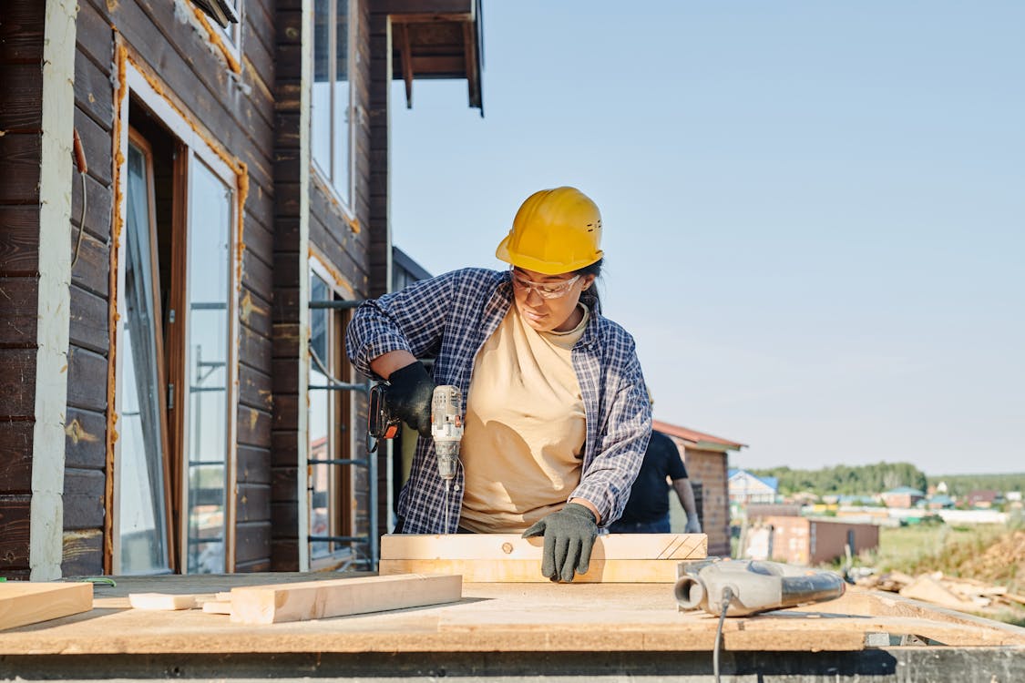 Free A Woman in Plaid Long Sleeve Shirt Holding a Power Tool Stock Photo