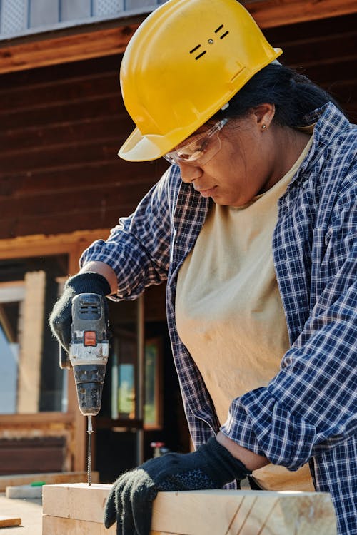 A Woman Holding a Power Tool Doing Woodworks