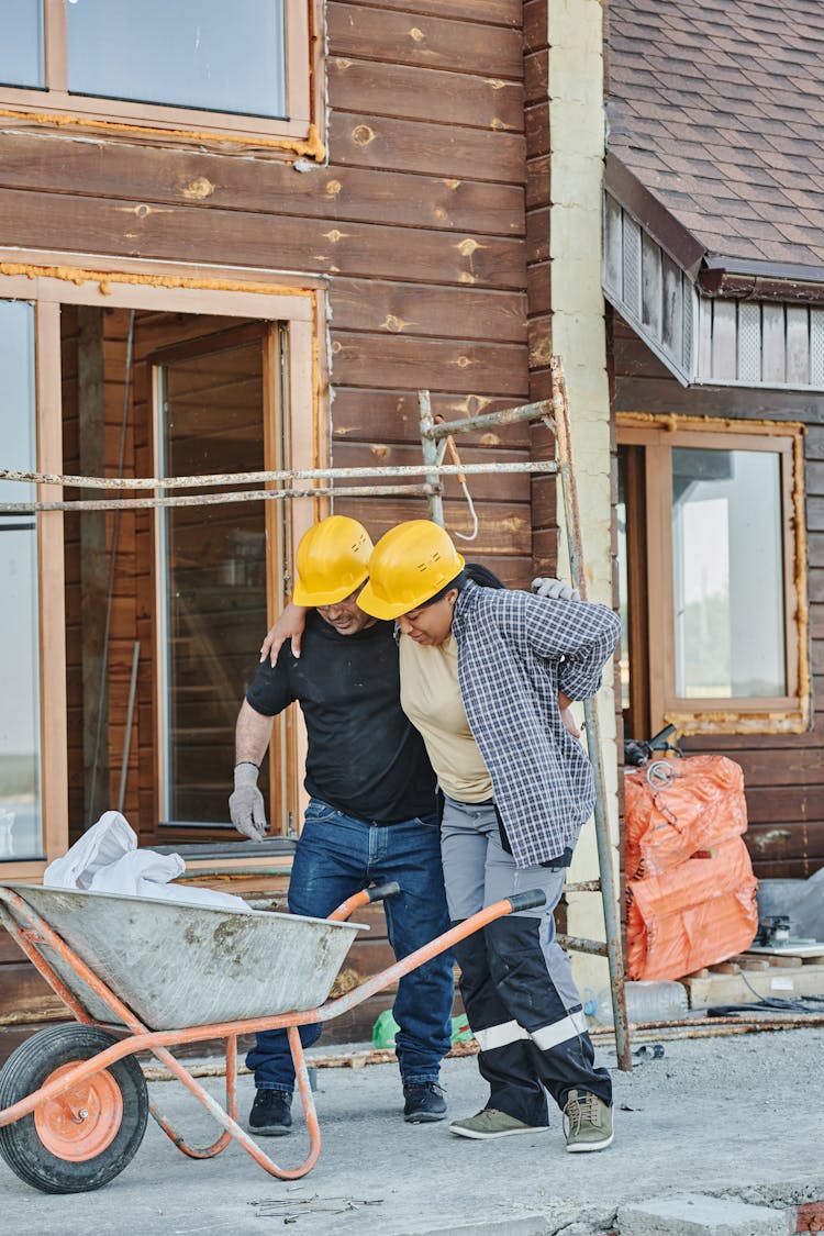 A Construction Worker Helping A Colleague Walk