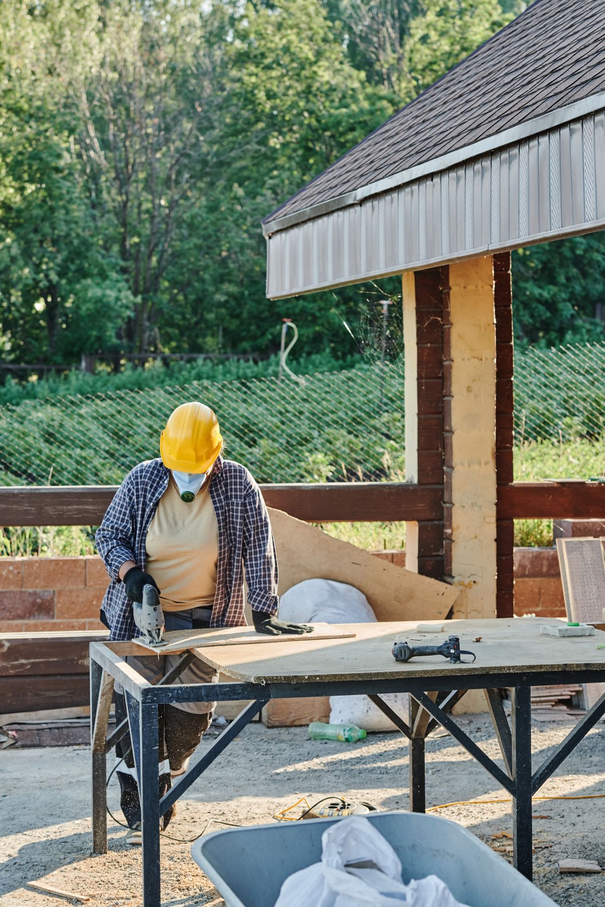 Construction worker cutting wood with a jigsaw on site