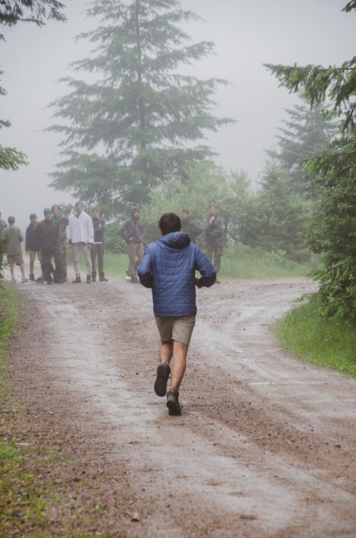 Man in Blue Jacket Running on Dirt Road in the Forest