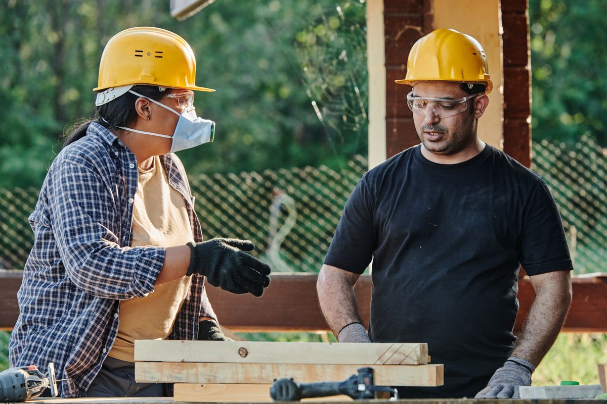 Two tradespeople discussing a work plan on site