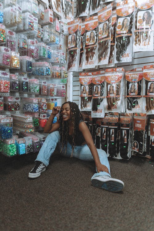 A Happy Woman in Denim Pants Sitting on the Floor