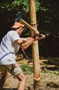 A Man Cutting a Wooden Pole with an Axe