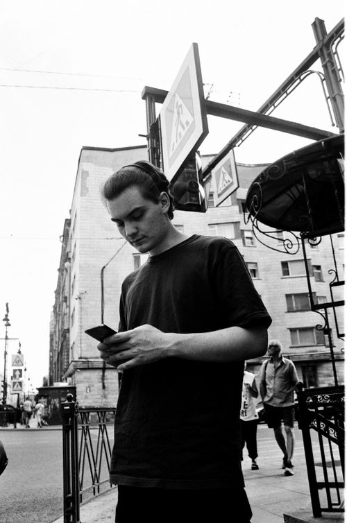 Free Black-and-white photo of a man using a smartphone on a city street. Stock Photo